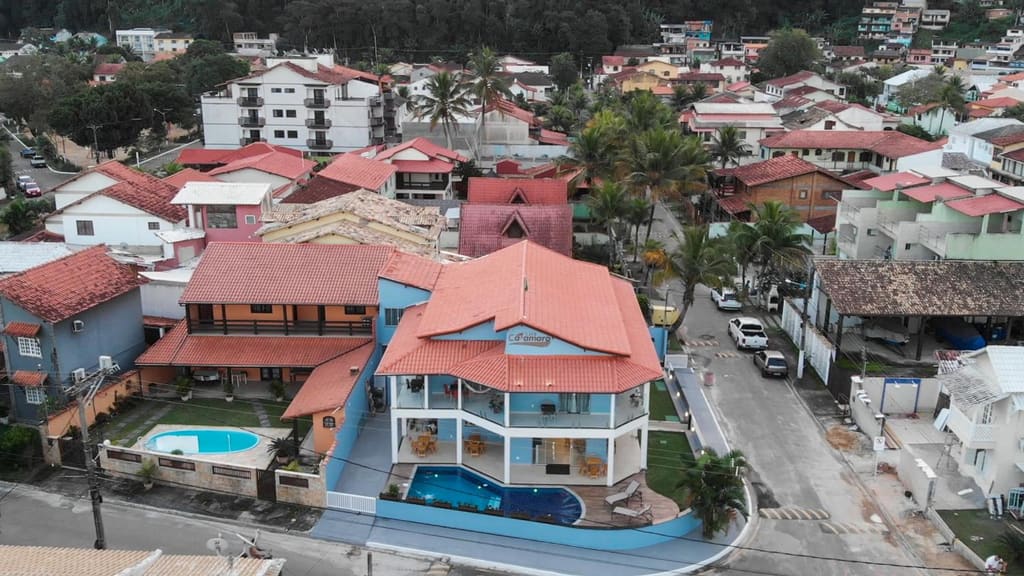 Vista de drone do Flats Catamarã, prédio azul de telhado vermelho com piscina, no Condomínio Garatucaia