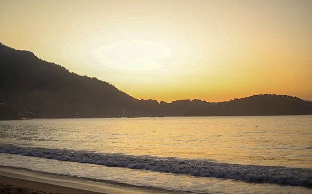Pôr do sol dourado sobre o mar da praia de Garatucaia