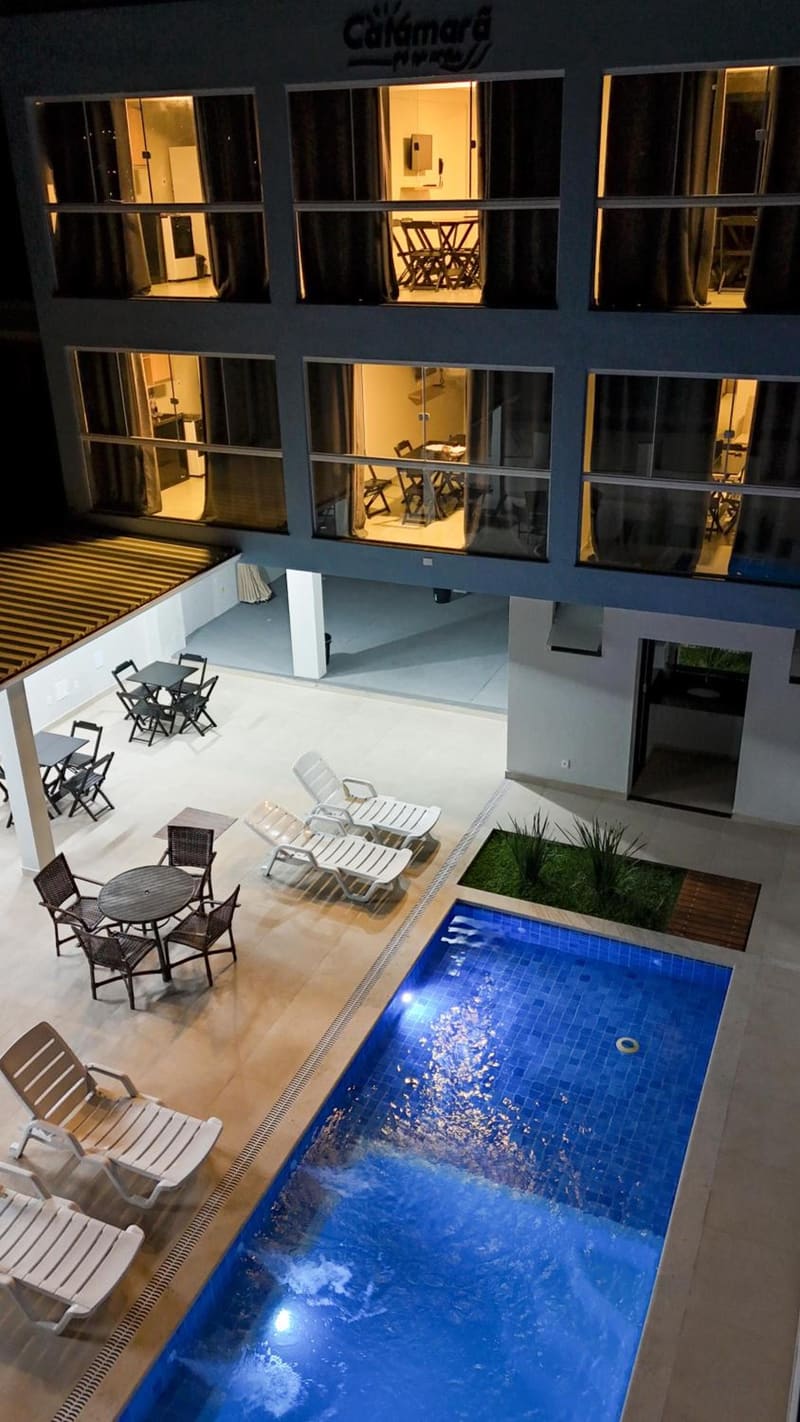 Piscina iluminada à noite no Catamarã Pé na Areia com mesas no deck